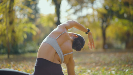 Woman performing a yoga stretching exercise in a vibrant autumn park, focusing on flexibility and...