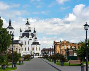 A street in a recreation park in a small Siberian town, bathed in autumn sunshine. At the end of the street is a church. Tourism in Russia