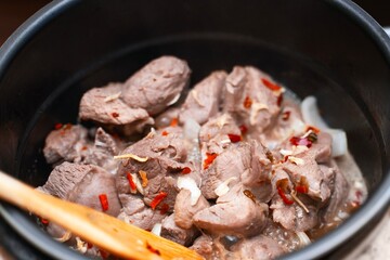 Meat with dried vegetables cooking in a deep metal pot or pan