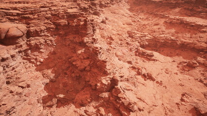 Dusty red formations stretch across the horizon, showcasing rugged cliffs and deep gorges bathed in warm light during the golden hour.