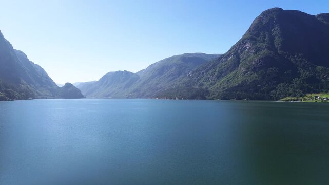 Drone rising from the ground and revealing the fjord in Odda, showing Sandvinvatnet with steep mountains, deep blue water, and dramatic Norwegian scenery.
