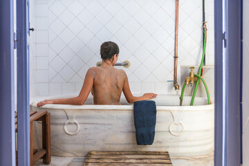 Woman enjoying clay treatment in a bathtub at a hot springs spa