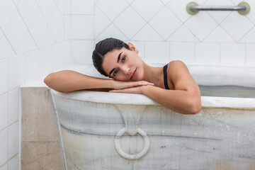 Woman relaxing in a marble bathtub at a serene hot spring spa