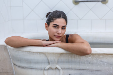 Woman relaxing in a bathtub at a hot spring spa, experiencing tranquility and wellness