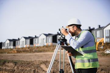 Land surveyor working with theodolite on construction site