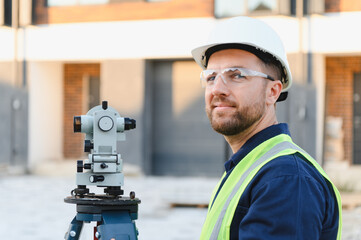 Surveyor using theodolite for land measurement