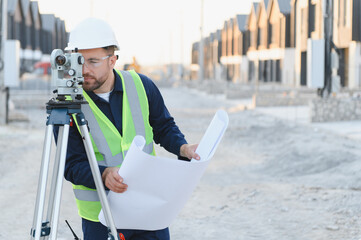 Surveyor working at new construction site with blueprint
