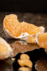 half of an orange citrus on a black mirror surface, ripe and sweet and juicy citrus is reflected on the surface, close up