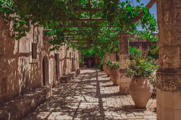 Shaded stone walkway with green vines at the Arkadi Monastery in Crete