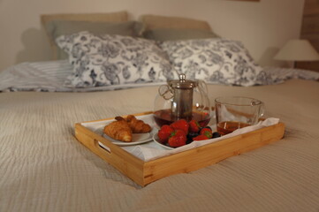 Warm and cozy evening scene with a fresh pizza on a table, lit candles, glass teapot with hot tea and a burning fireplace in the background. Soft ambient lighting creates a relaxing, home-like atmosph