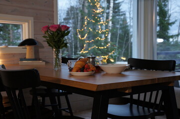 Warm and cozy evening scene with a fresh pizza on a table, lit candles, glass teapot with hot tea and a burning fireplace in the background. Soft ambient lighting creates a relaxing, home-like atmosph