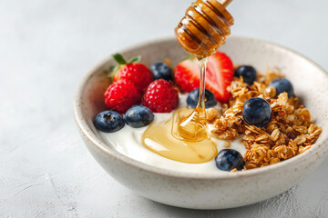 Granola bowl with creamy yogurt, fresh blueberries, raspberries, and honey drizzle, captured in soft natural light for wholesome breakfast and food imagery.