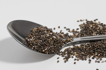 Chia seeds in a silver spoon on a white background
