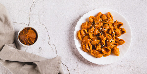 Delicious shell pasta with miso paste on a plate on the table top view web banner