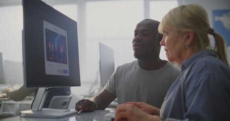 In Bright Modern Classroom, African American Instructor Helps Older Female Student Use AI Software Design Futuristic City Artwork. Concept of Lifelong Learning, Creativity, Modern Technology Skills.