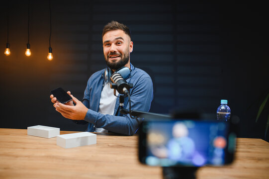 Video blogger recording smartphone review in home studio