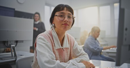 Focused on Screen South Asian Woman in Glasses Sits at Computer During Coding Class, Smiling. Concept Lifelong Learning, Digital Literacy, Professional Development, and Modern Education. Portrait.