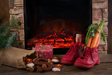 Obraz premium Saint Nicholas - Sinterklaas shoe with carrot and sweets near the fireplace