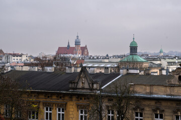 Naklejka premium Krakow cityscape featuring historic buildings and domes under a cloudy sky.