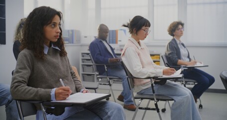 Diverse Adult Learners Concentrated on Writing Task During Lesson in Classroom. Concept of Modern Learning Environment Promoting Inclusion, Skill Growth, and Educational Progress. Dolly Shot.