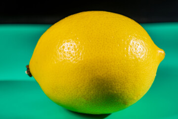 A vibrant yellow lemon resting on a table, captured in soft natural light. The image highlights the fruit&rsquo;s bright color, fresh texture, and simple composition, making it suitable for food photography