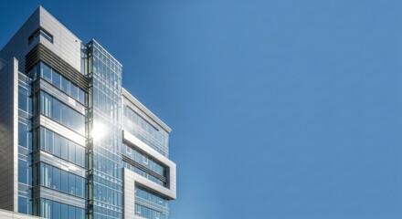 Modern corporate architecture with glass facade reflecting sunshine against blue sky