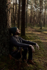 Man Sitting Against Tree in Forest, Enjoying Peaceful Moment