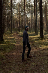 Man walking in a forest at sunset, with sunlight filtering through the trees