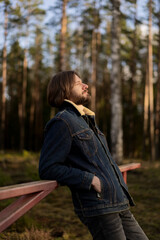 Man Enjoying the Outdoors, Leaning on Fence in Forest