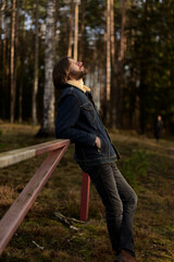Man Enjoying the Outdoors, Leaning on Fence in Forest