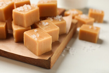 Tasty caramel candies with salt on light table, closeup