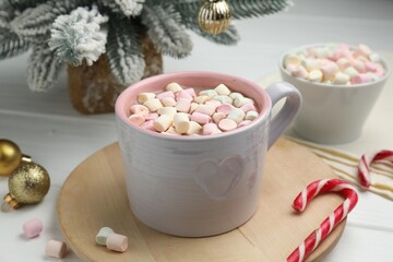 Tasty cocoa with marshmallows and Christmas decor on white wooden table, closeup