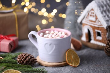Tasty cocoa with marshmallows and Christmas decor on grey table against blurred lights, closeup