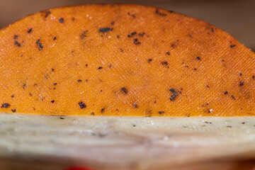 Slices of semi-hard cheese arranged neatly with fresh basil leaves on top. The combination of creamy-yellow cheese and vibrant green basil creates a clean, appetizing visual contrast.