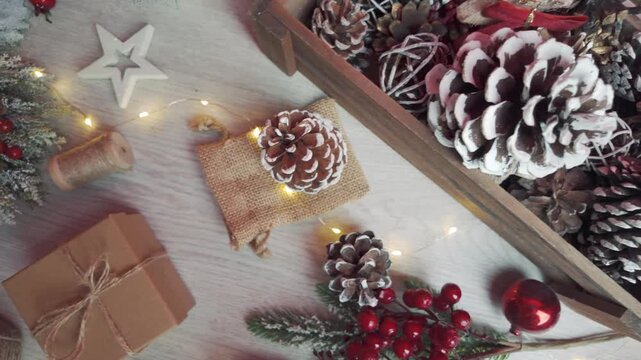 Top-view camera glides left over arranged Christmas decorations, revealing a cozy festive tabletop scene