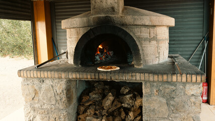 Wood-fired oven with glowing coal and beautiful flames, featuring a fresh Margherita pizza at the oven mouth. Authentic Italian cooking, rustic and inviting.