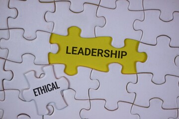 Fototapeta premium puzzle pieces with a yellow piece in the center labeled “LEADERSHIP,” accompanied by another piece labeled “ETHICAL,” symbolizing the connection between strong leadership and ethical principles.