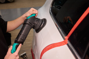 Polishing black car surface thoroughly, Detailed buffing to achieve showroom quality shine, Expert technician uses orbital buffer and foam pad to enhance vehicle gloss