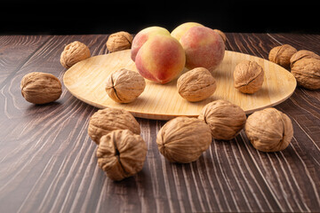 Walnuts and peaches, walnuts in their shells and peaches arranged on a rustic table, Selective Focus.