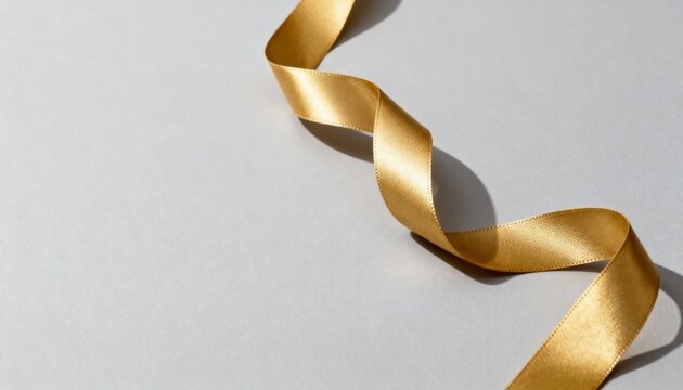 Shiny gold ribbon for Christmas decoration. Elegant curled satin streamer on a grey background with copy space for text - Powered by Adobe