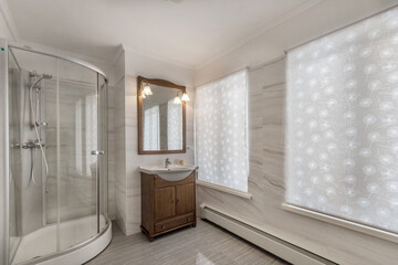 Modern bathroom with two windows. Dark furniture and a glass shower cabin.