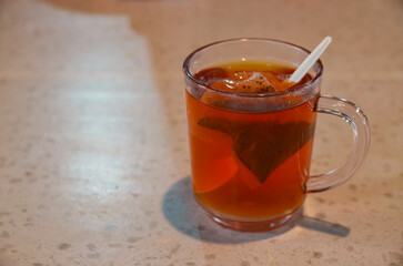 A Cozy Moment of Respite: A clear glass mug filled with steeping amber tea, complete with a stirrer, offers a warm and inviting pause.