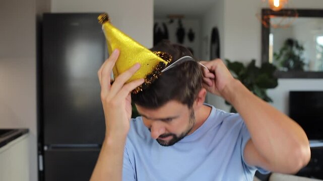 Clumsy man trying to put a festive birthday hat on 