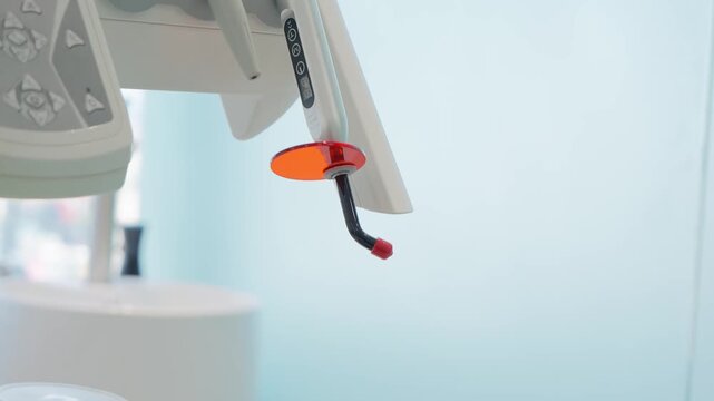 Close-up of a modern dental unit with various professional instruments. The focus is on a dental polymerization curing light in a clean clinic