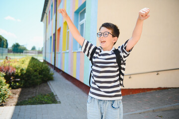 Happy pupil celebrating back to school outside colorful building
