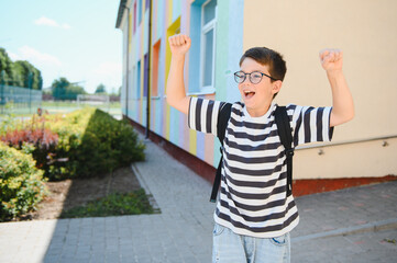 Enthusiastic student celebrating back to school near colorful building