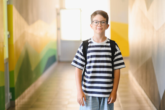 Smiling pupil wearing backpack standing in school hallway - Powered by Adobe