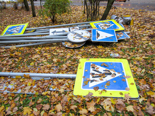 Road signs lie on the ground covered with autumn leaves.