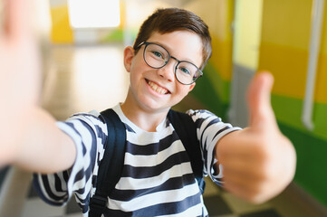 Smiling student taking selfie and giving thumbs up at school