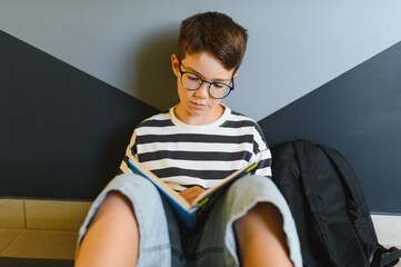 Elementary school student reading a book in the hallway